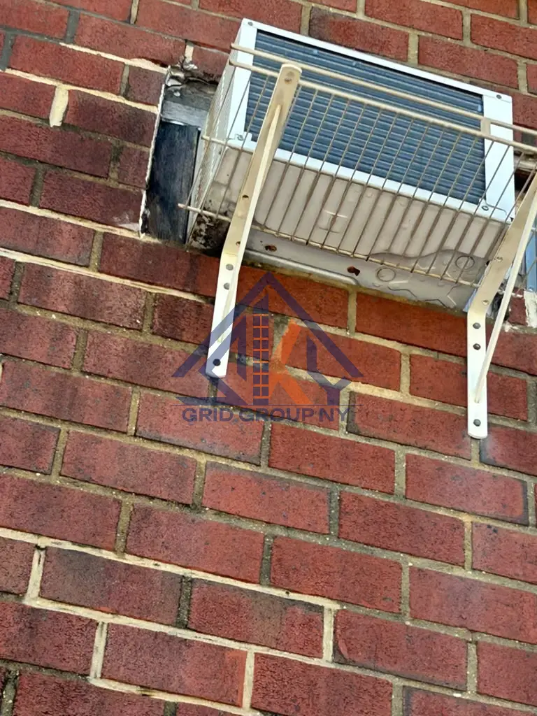 Open gaps and worn mortar around a through-wall air conditioner sleeve on the brick facade at 46-11 88th Street, Elmhurst