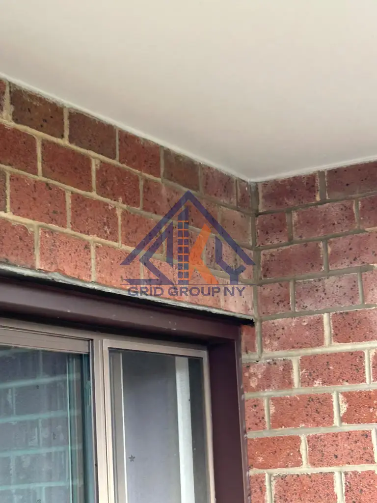 Repointed brick joints where two walls meet below a ceiling on the Elmhurst building