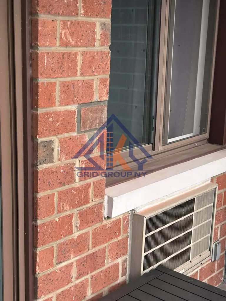 Repointed brickwork beside a window and air conditioner grille on the Elmhurst building